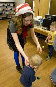 Albert Lea Public Library employee Deb Dyvig places a plastic medal on Isaac Hovde after Isaac completed an egg spoon race as part of the birthday celebration for Dr. Seuss Thursday. -- Sarah Stultz/Albert Lea Tribune