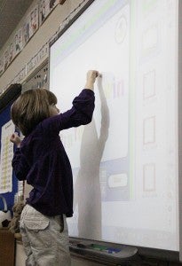 A student in Peggy Bennett’s first-grade class at Sibley  Elementary School uses a Smart Board to practice spelling.