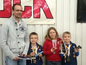 Ryan Hillman, Kenny Hillman, Mikayla Hillman and Easton Hillman pose for a photo with the trophies they won at a pinewood derby race recently.