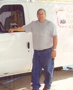 Jim Grunewald, who retired in January from G&G Heating and Air Conditioning, stands beside a company truck.