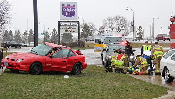 Emergency medical technicians assist the injured driver of a Pontiac Sunbird on a wet and rainy Monday in front of Taco John's at the corner of Main Street and Prospect Avenue in Albert Lea. -- Tim Engstrom/Albert Lea Tribune