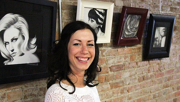 Artist Angie Hoffman smiles Thursday in front of pencil drawings she has hanging up at Prairie Wind Coffee in downtown Albert Lea. The image to the left is a portrait of January Jones, an actress of the TV show “Mad Men.” --Tim Engstrom/Albert Lea Tribune