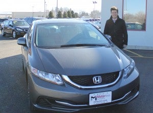 Jonathan Breuer, salesman at Motor Inn Company, stands with his favorite car on the lot: A Honda Civic. Breuer really likes the gas mileage with the Civic.
