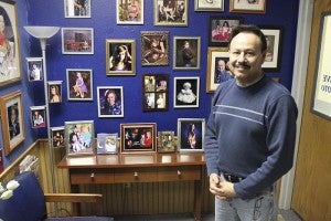 Steve Tovar stands in front of portraits he has taken. His love of cameras led him to start his business. Maintaining the latest technology allows him to have new approaches and implement fresh ideas.