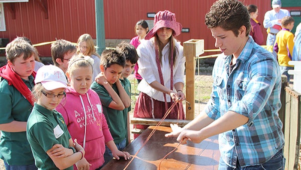 Corbin Schultz, right, and Anna Anderson, back, teach fifth-graders from St. Theodore Catholic School all about rope making during Discover History Days at the Freeborn County Historical Museum. --Kelli Lageson/Albert Lea Tribune