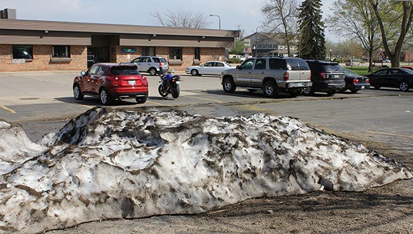 In a show of contrasts, a snowbank in the parking lot of Security Bank Minnesota in Albert Lea melts in 100-degree heat Tuesday afternoon. The snow was a reminder of a foot of snow that fell in the city 10 days prior. -- Tim Engstrom/Albert Lea Tribune