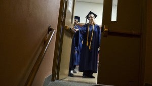 A pair of Riverland graduates peak in through a door during the 2013 commencement Friday night in Knowlton Auditorium. -- Eric Johnson/Albert Lea Tribune