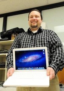 Ryan Welch, the director of technology for Northwood-Kensett schools, holds up a laptop that students use as part of the school’s laptop program.
