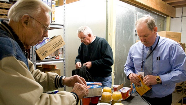 Daybreakers Kiwanis volunteers, from left, Rex Stotts, Phil Hintermeister and Mark Fenstermacher load up backpacks with food at the Albert Lea Salvation Army for eight families to take home over the weekend in early February.  --Sarah Stultz/Albert Lea Tribune