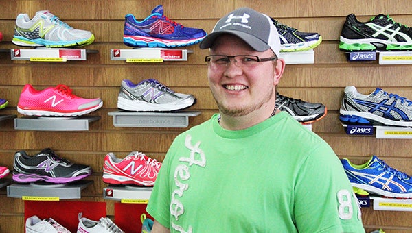 Jordan Flatness stands Monday in front of New Balance and Asics shoes for sale at Tiger City Sports. --Tim Engstrom/Albert Lea Tribune