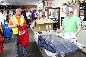 Tiger City Sports Manager Jordan Flatness, right, assists Steve Kloos of the Wells Parks and Recreation Department in buying baseball gear for children in kindergarten through sixth grade Monday.