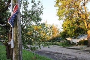 By wrapping around its bracket, an American flag remains flying Thursday morning along Minnesota Highway 109 after a storm hit Wells Wednesday evening. In the background, trees are down at Midwest Dental. -- Tim Engstrom/Albert Lea Tribune