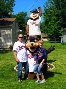 Tom and Sandy Schroeder of Wells stand with the Minnesota Twins mascot, T.C., in front of their T.C. Bear wood carving in their yard in Wells. 
