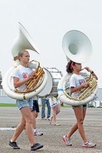 Emma Behling, left, and Abby Sencio, right, practice marching on Wednesday. The band runs through their routine in the high school parking lot.