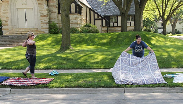 Tara Luna, right, lays a blanket in the boulevard strip Tuesday along Bridge Avenue in front of Zion Avenue while her sister, Theresa Sullivan, watches. -- Tim Engstrom/Albert Lea Tribune