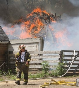 Austin Fire Department Cmdr. Tom Schulte communicates with firefighters as a shed burns on the Joe Sheedy property northwest of Austin Tuesday afternoon.