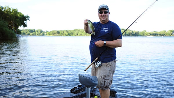 Jason Howland stands on his 1988 Champion bass fishing boat as he holds a smallmouth bass he caught Friday in Edgewater Bay at Fountain Lake in Albert Lea. Howland finished in 11th place this year at the Bass Fishing League All-American tournament. — Micah Bader/Albert Lea Tribune