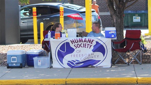 Freeborn County Humane Society volunteers chat on Friday at a booth on the corner of Broadway and Main. The Buckets on Broadway fundraiser raised a little more than $5,000 for the shelter. The goal was $10,000. -- Erin Murtaugh/Albert Lea Tribune