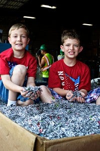 Hunter Kreutzbender, right, and his brother, Kyle, pose for a photograph with a large pile of pop tabs on June 20 before the money from the tabs was donated to The Ronald McDonald House. –Photo courtesy Natasha Clarey Photography