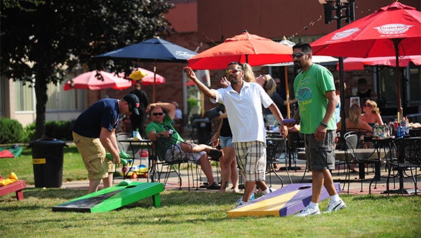 Lennie Aguilera throws a beanbag, while Pedro Olvera waits for his turn during a tournament Sunday in the Big Island Grill and Bar courtyard. — Micah Bader/Albert Lea Tribune