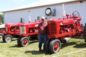 Marvin Thompson stands with his Farmall tractors. Thompson has six antique tractors on display at the fair this year. -- Erin Murtaugh/Albert Lea Tribune