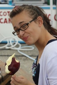 Intern Quinn Andersen tries a taffy apple from Tonka Taffy. --Erin Murtaugh/Albert Lea Tribune