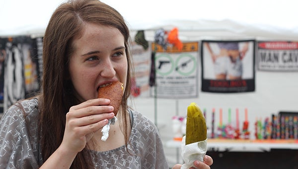 Intern Erin Murtaugh tries a cheese pup while holding a pickle on a stick. --Quinn Andersen/Albert Lea Tribune