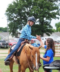 Missy Malakowsky of Hartland does a handshake with her friend Haylie Mosher of New Richland from atop her horse.