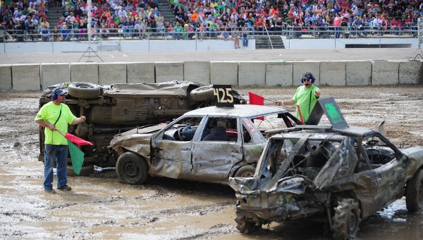 Hard hitting at the Freeborn County Fair demolition derby Sunday in front of a packed house led to a stoppage of action in the compact division. Nick Schreiber (middle) allows officials to put all four wheels of Matt Nicholson's ride back into the mud. Schreiber took seventh, and despite being kocked on his side in the early going, Nicholson took second. — Micah Bader/Albert Lea Tribune       