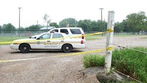 Police tape marks off one of the entrances to Swensrud Park Monday afternoon as two Worth County Sheriff's Office deputies talk near their cars. -- Sarah Stultz/Albert Lea Tribune    