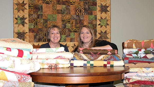 Kim Zenk and her daughter Katie Hebblewhite pose with a few of the 135 quilts they helped make that will be auctioned off to raise money for the Good Earth Village in Spring Valley on Aug. 17. --Quinn Andersen/Albert Lea Tribune
