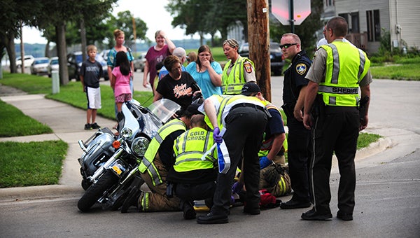 Residents near the intersection of Frank Avenue and Third Street watch Saturday as the operator of a motorcycle is moved to a stretcher and taken away in an ambulance. -- Micah Bader/Albert Lea Tribune     