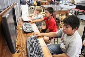 Abraham Baltazar, 11, (in foreground), and Jesse Baltazar, 9, play online games next to Adrey Lidell, 7, on Tuesday afternoon at The Rock. In the next room, several children watched a movie on a TV set.