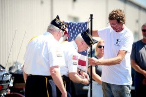 Bryce Haugland, right, holds a flagpole while Dave Olson of the American Legion Post 56 unclips the flag so it could be folded and placed on display at Bergdale Harley-Davidson on Monday.