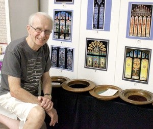 Art Center member Tom Mullen poses next to some installments at the latest art center exhibit: “Art & Faith.” Mullen helped find the photos, paintings, banners and other pieces from area churches.