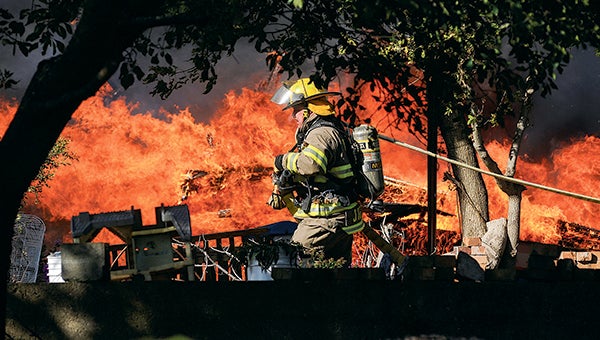 An Austin firefighter runs a hose in front of burning barn at the residence of Daniel Borgen, 50718 195th St., Wednesday afternoon. --Eric Johnson/Albert Lea Tribune