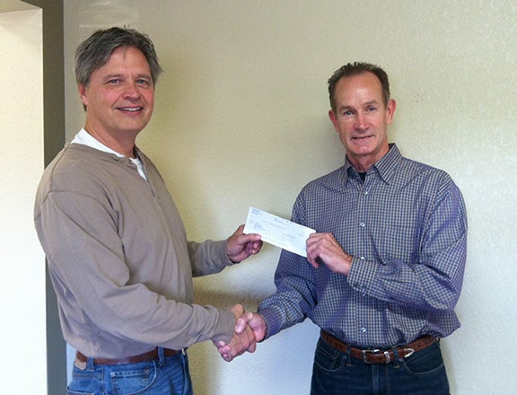 Jim Troe, left, accepts a $4,000 check from Ken Petersen. Petersen’s employer Hubbard Feeds made the donation to help with the 2014 Shinefest activities. --Submitted