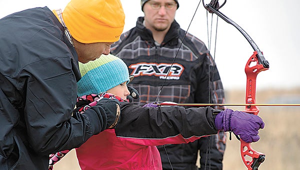 Fifth-grader Lily Miller gets aiming help from Tom Larson and Alex Thysell during Governor’s Deer Opener activities at the Prairie Wetlands Learning Center on Friday. --Dave Churchill/Fergus Falls Daily Journal 