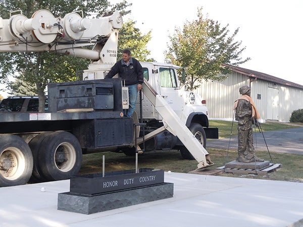Brandon Diedrich, on a Diedrich Ag crane, gets ready to set the large memorial stone and life-sized soldier statues. -- Submitted 