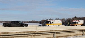 A black Chevy pickup sits on the southbound Interstate 35 bridge over Albert Lea Lake on Tuesday morning after it crashed. Ambulances prepare to carry the injured to the Albert Lea hospital.
