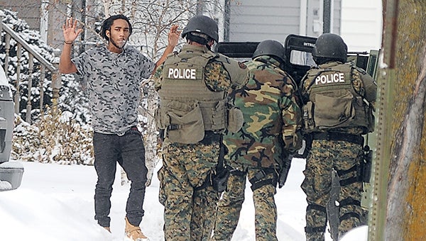 A 17-year-old approaches members of the Austin Special Incident Reponse Team after leaving the home of a standoff on Eighth Avenue NW Tuesday afternoon. The teenager was one of two people arrested at the home. --Eric Johnson/Albert Lea Tribune