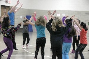The class jumps to warm up before learning a new dance.  The class will perform in February. 