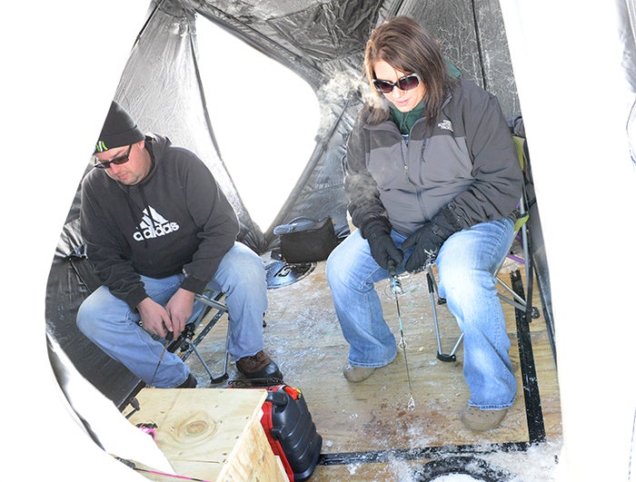 Aaron and Emily Williamson of Glenville fish out of their icehouse Thursday afternoon on Fountain Lake .