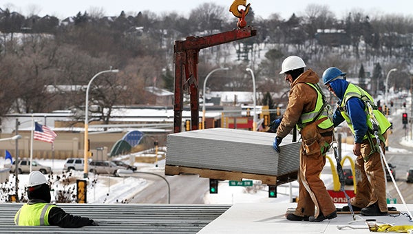 Construction workers Jack Sullivan and Jeremy Sommer, right, move slabs of concrete flooring towards Mausoon Hussain, bottom left, at the site of what will be a Homewood Suites hotel Friday in Rochester. The hotel will be across the street from Mayo Clinic Hospital, Saint Marys Campus, and is one of the first signs of Rochester’s growth since the state Legislature approved the Destination Medical Center initiative last year. -- Alex Kolyer/for MPR News 