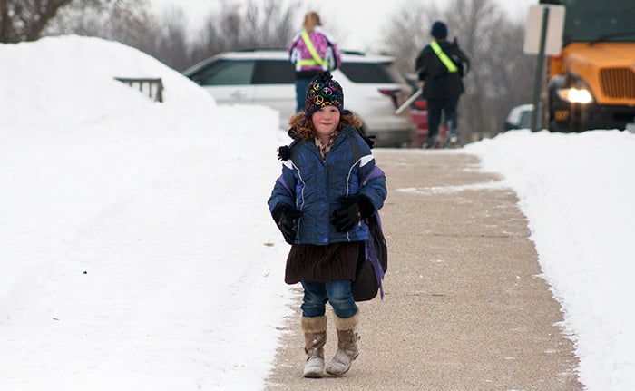 Jenna Blofe, 6, walks down the sidewalk outside of Sibley Elementary School on Tuesday toward her mother's automobile. --Colleen Harrison/for the Tribune