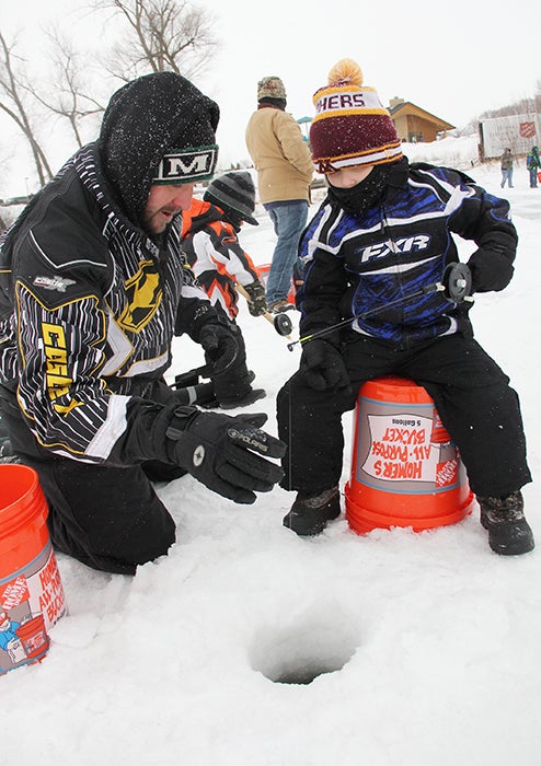 Derek Sternhagen helps his son Derek, 4, and Ashton, 2, back, ice fish Saturday morning on Edgewater Bay as part of Take a Kid Ice Fishing, one of the events of The Big Freeze. --Sarah Stultz/Albert Lea Tribune 