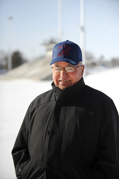 Jerry Kaphers, a volunteer assistant with the Albert Lea track and field team, stands Friday on the east side of the Tigers' snow-covered track wearing the baseball cap he was presented with for during his induction into the Minnesota State Track and Field Coaches Hall of Fame. -- Micah Bader/Albert Lea Tribune