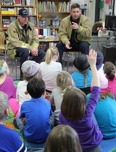 Albert Lea firefighter Bart Berven, right, calls on a student with her hand up Monday at Sibley Elementary School as community members read Dr. Seuss books to Sibley Elementary School students. With him is firefighter Chris Harveaux. -- Tim Engstrom/Albert Lea Tribune 