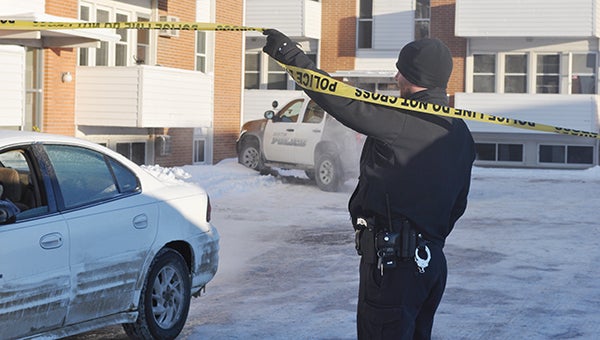 Officer Mark Walski lifts police tape to let a car leave the lot of Park Place Commons at 201 11th Ave. NW Monday morning. The Austin Police Department had been on scene since Sunday night, as a man had barricaded himself inside an apartment unit.  -- Trey Mewes/Albert Lea Tribune