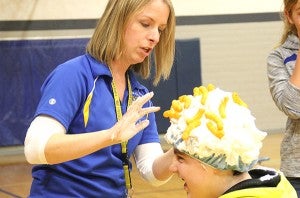 FFA adviser Angie James counts the cheese puffs on a student's head. – Tiffany Krupke/Albert Lea Tribune